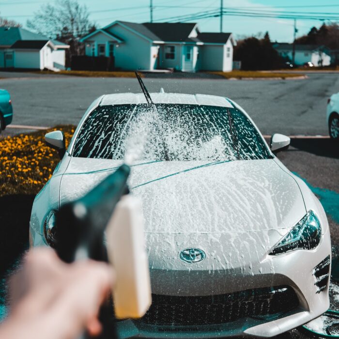 person spraying water on vehicle